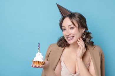 Photo of Birthday celebration. Woman with cupcake on light blue background