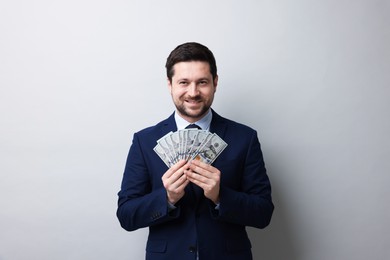 Photo of Happy greedy banker with dollar banknotes on grey background