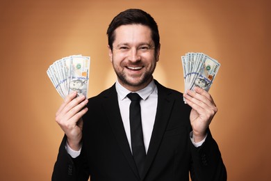 Photo of Happy greedy banker with dollar banknotes on golden background