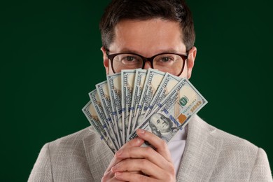 Photo of Greedy banker with dollar banknotes on green background, closeup
