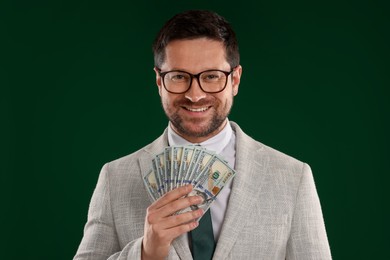 Photo of Happy greedy banker with dollar banknotes on green background