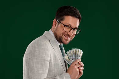 Photo of Happy greedy banker with dollar banknotes on green background