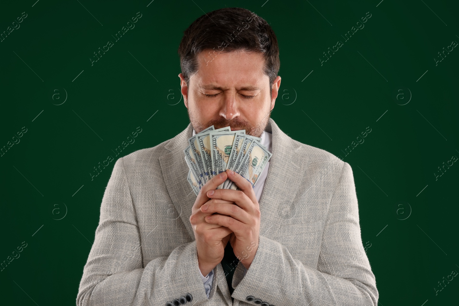 Greedy banker with dollar banknotes on green background Photo of Greedy banker with dollar banknotes on green background