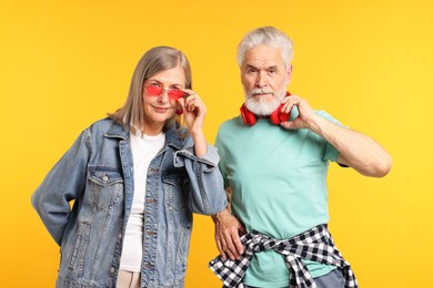 Photo of Senior couple in stylish outfits on orange background