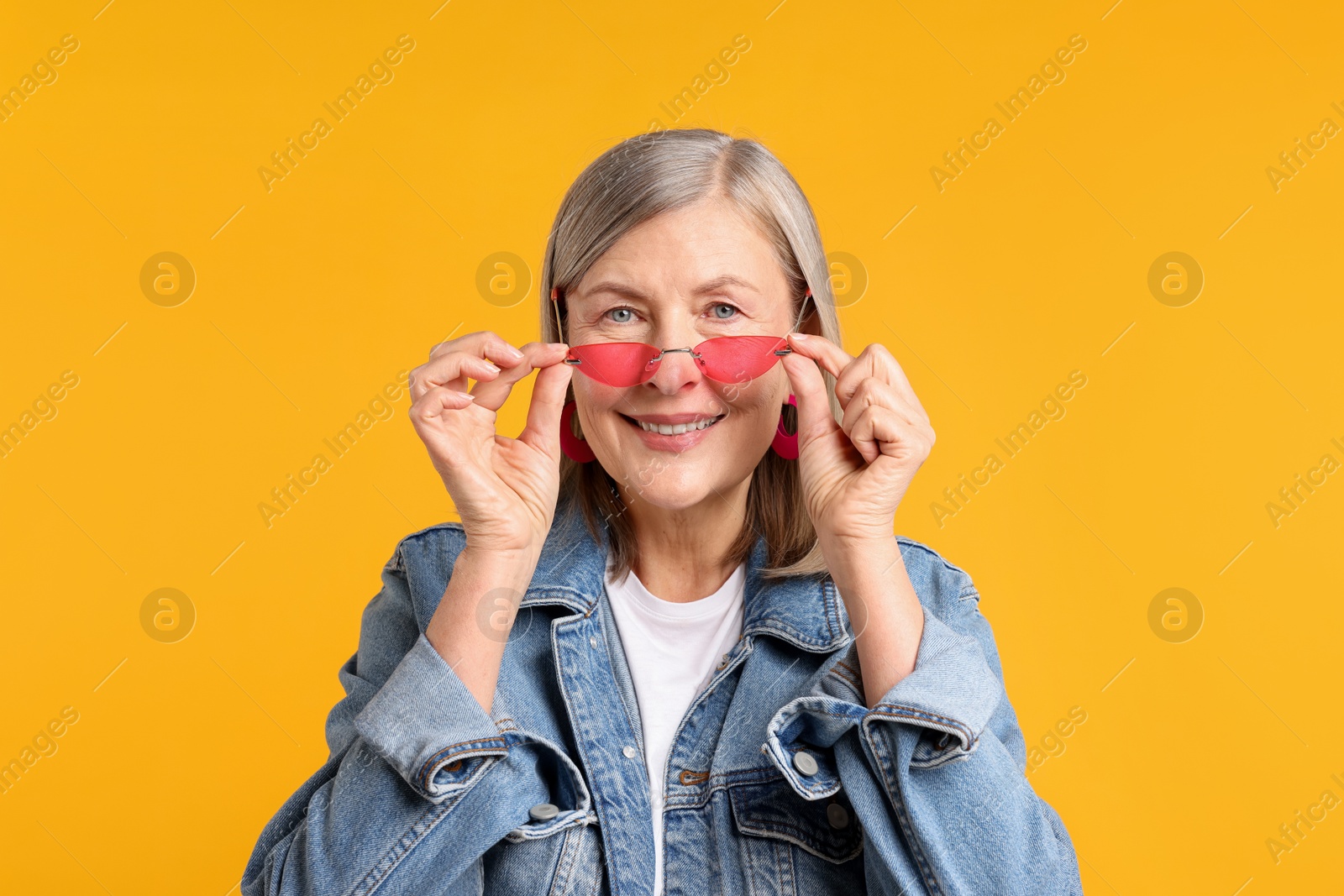 Senior woman wearing stylish sunglasses on orange background Photo of Senior woman wearing stylish sunglasses on orange background