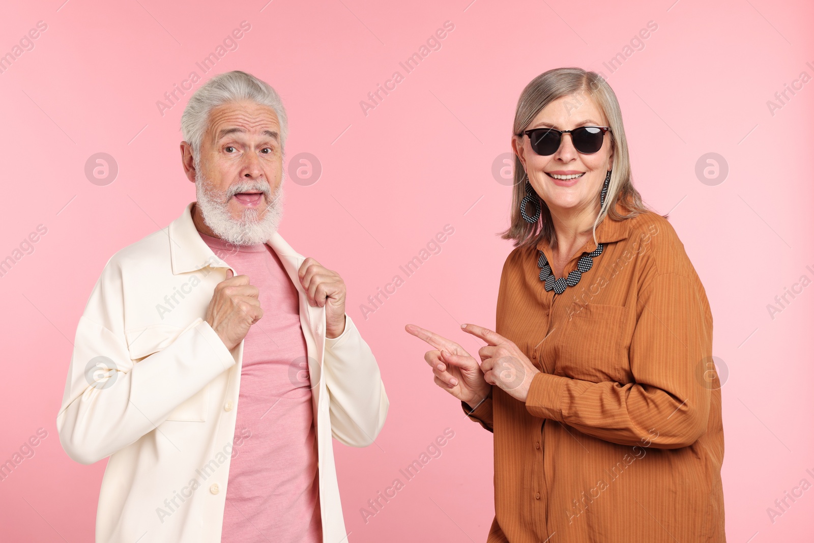Senior couple in stylish outfits on pink background Photo of Senior couple in stylish outfits on pink background