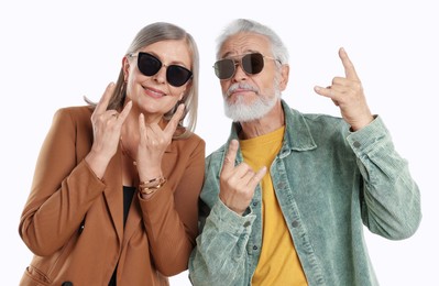 Photo of Senior couple in stylish outfits making rock gestures on white background