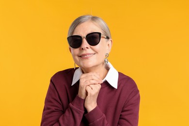 Photo of Happy senior woman in stylish outfit on orange background