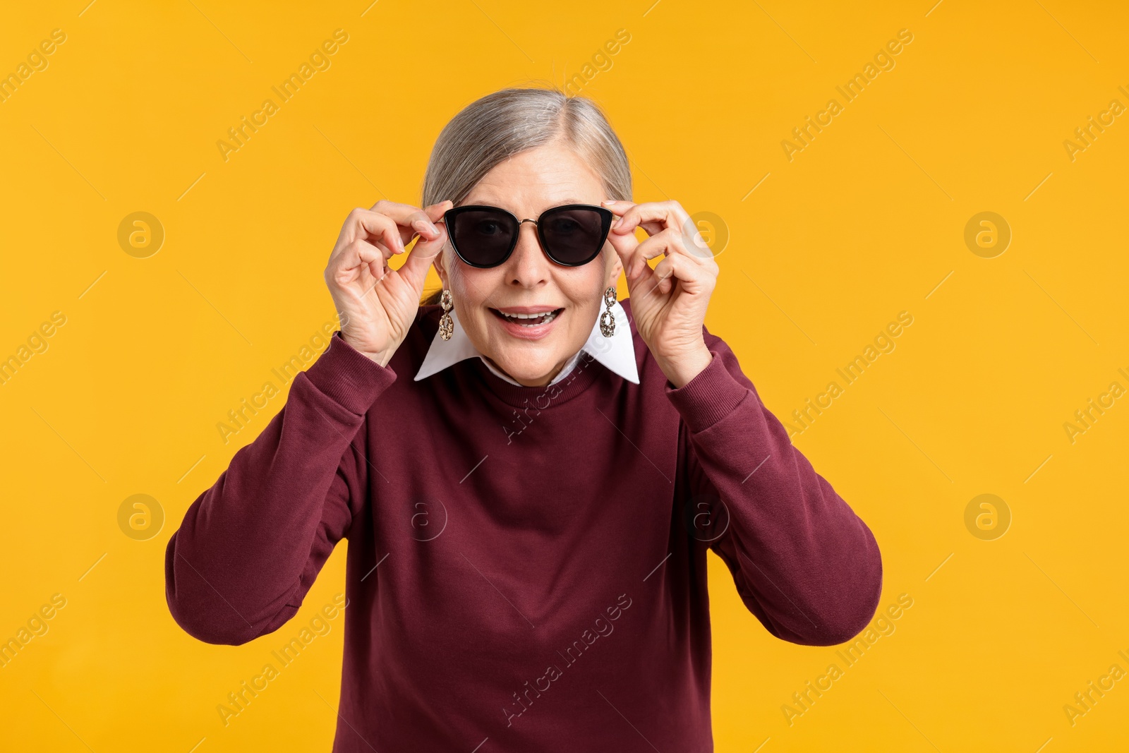 Happy senior woman in stylish outfit on orange background Photo of Happy senior woman in stylish outfit on orange background