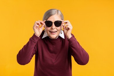 Photo of Happy senior woman in stylish outfit on orange background