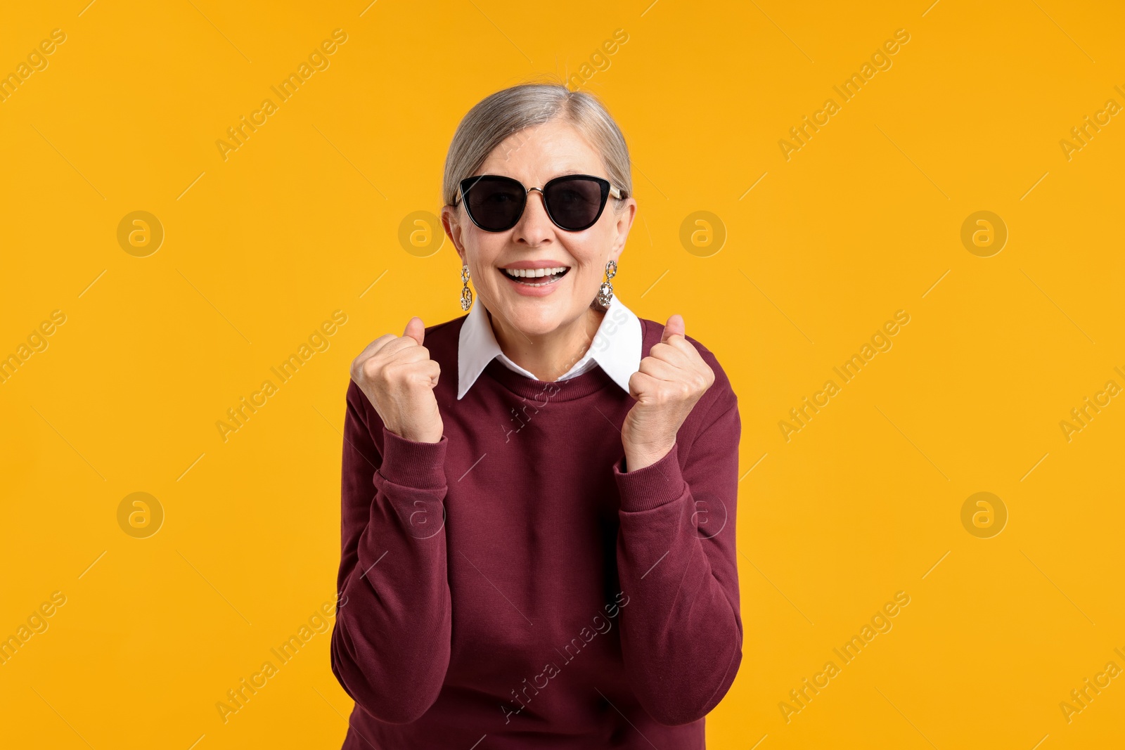 Happy senior woman in stylish outfit on orange background Photo of Happy senior woman in stylish outfit on orange background