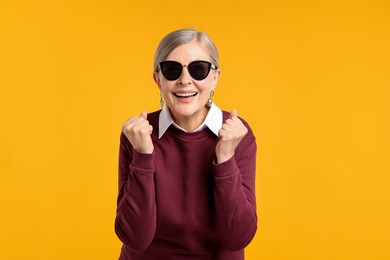 Photo of Happy senior woman in stylish outfit on orange background