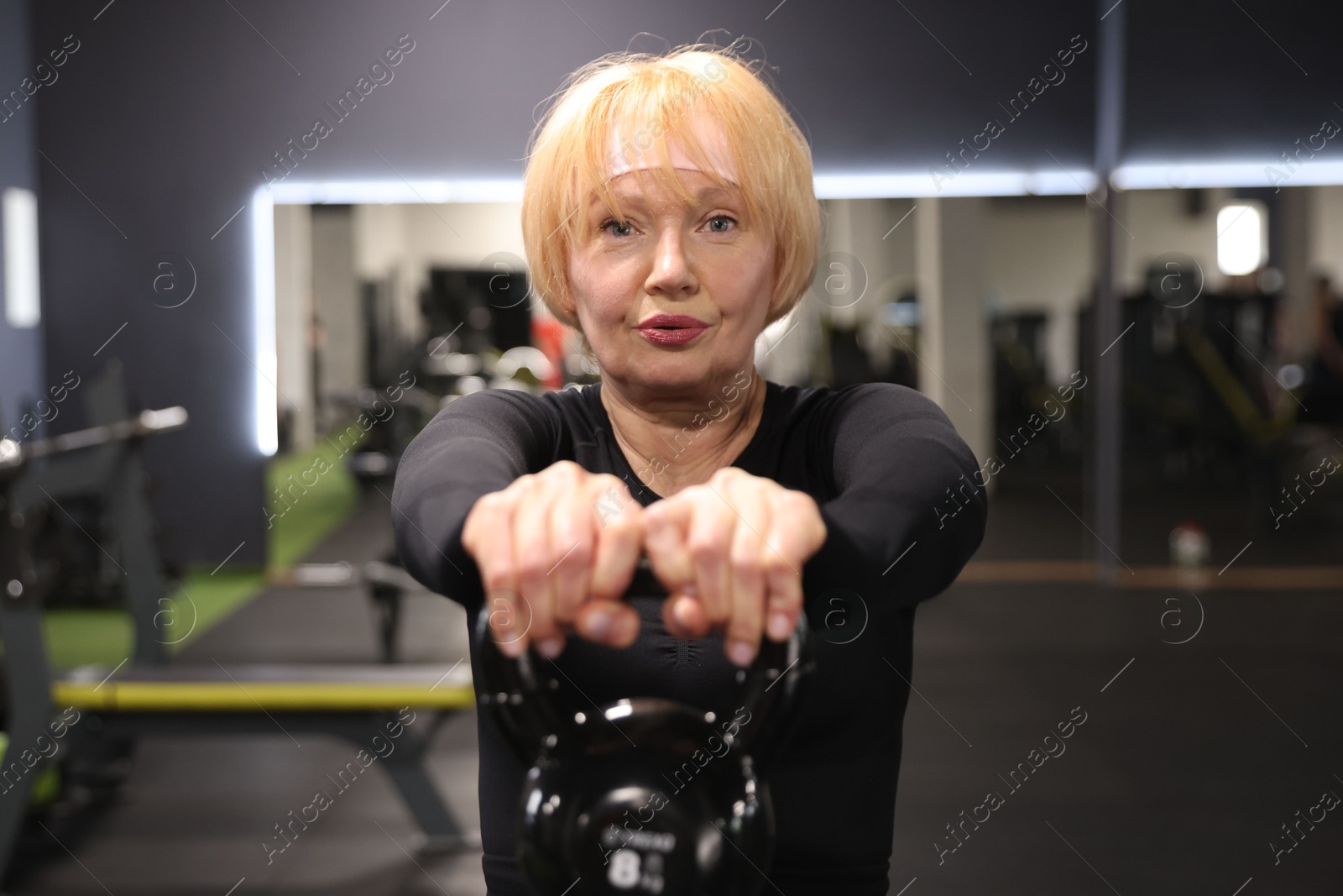 Senior woman training with kettlebell in gym Photo of Senior woman training with kettlebell in gym