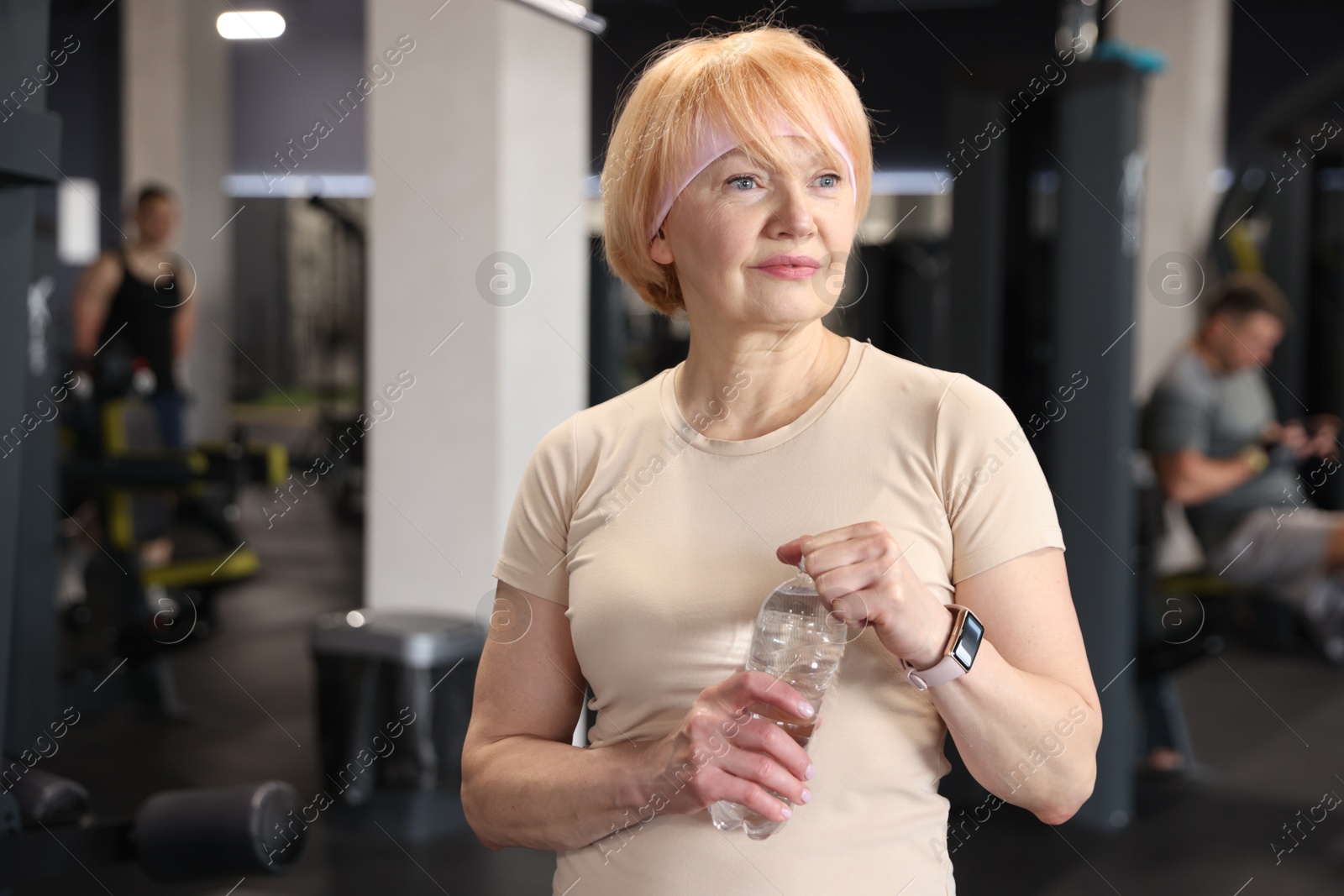 Senior woman with bottle of water in gym Photo of Senior woman with bottle of water in gym