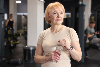 Photo of Senior woman with bottle of water in gym