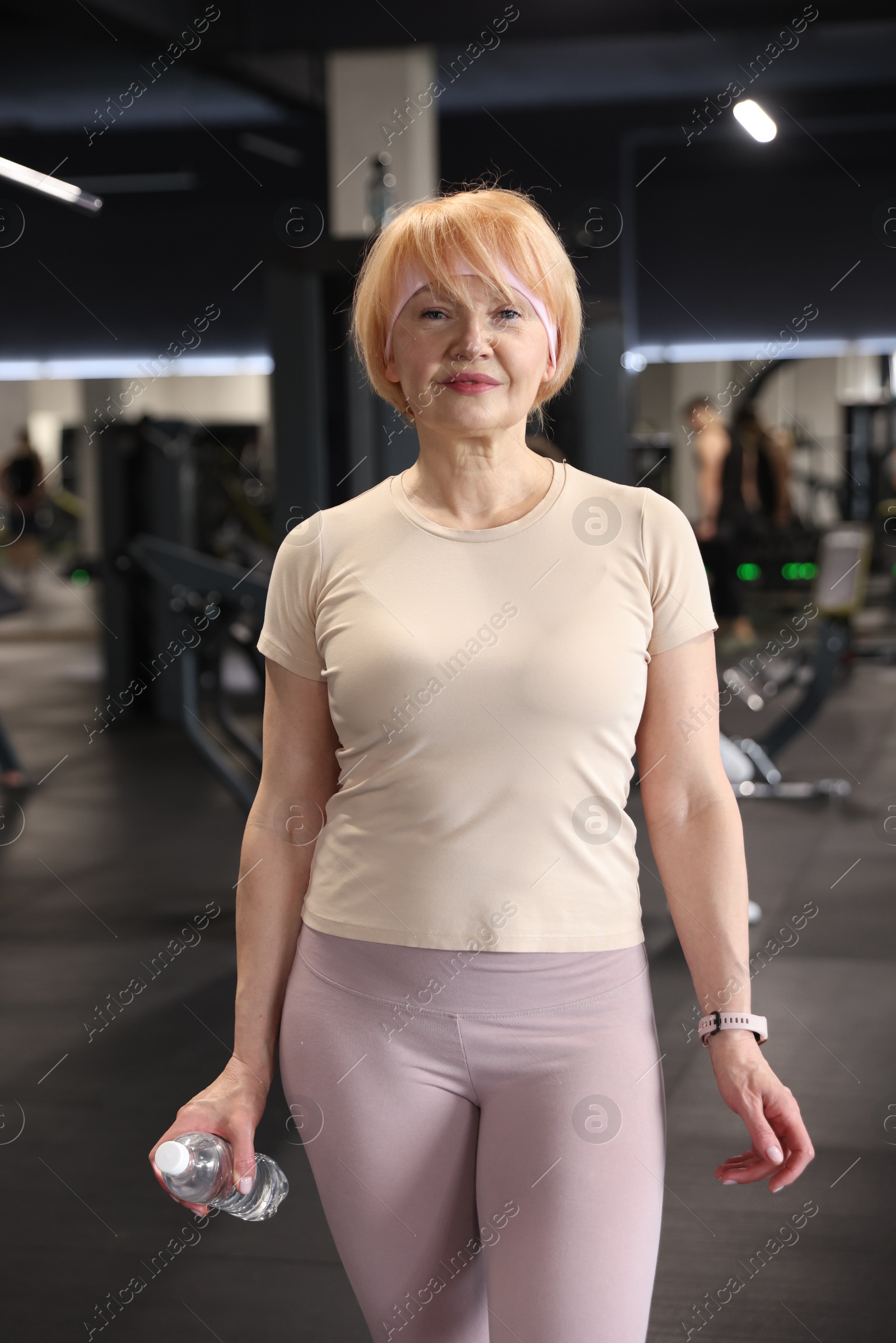 Senior woman with bottle of water in gym Photo of Senior woman with bottle of water in gym