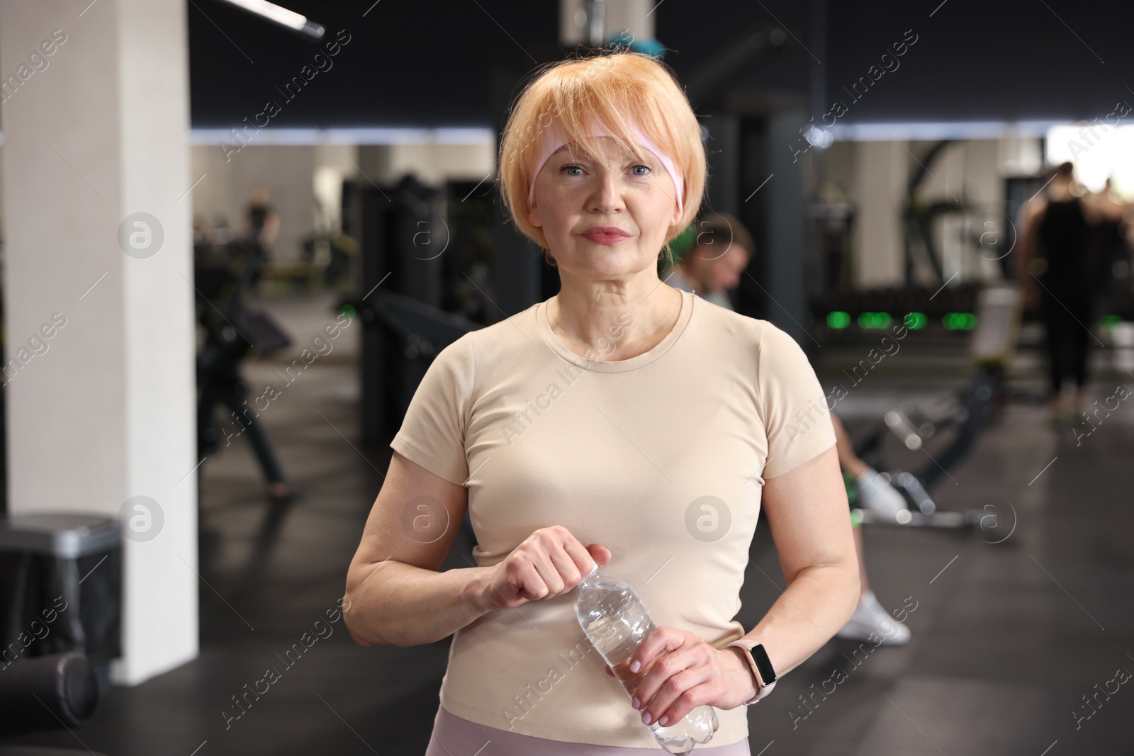 Senior woman with bottle of water in gym Photo of Senior woman with bottle of water in gym