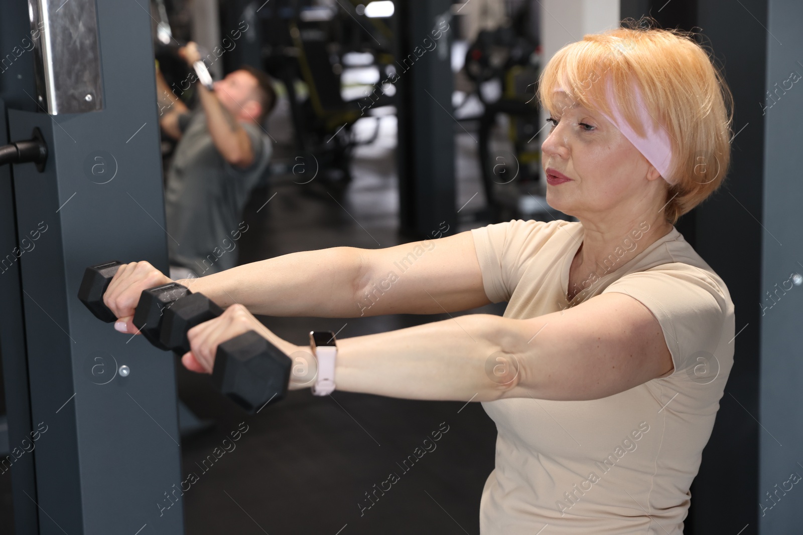 Senior woman training with dumbbells in gym Photo of Senior woman training with dumbbells in gym