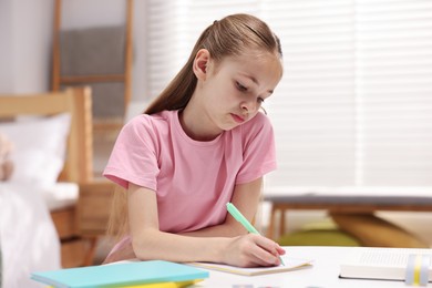 Photo of Dyslexia. Little girl writing at table indoors