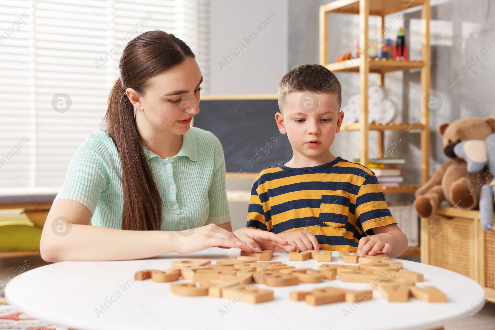 Dyslexia. Mother and her son learning letters at table indoors Photo of Dyslexia. Mother and her son learning letters at table indoors