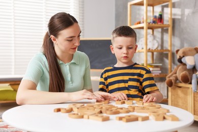 Photo of Dyslexia. Mother and her son learning letters at table indoors