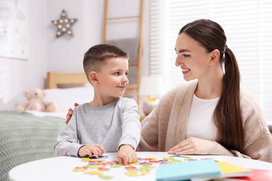 Photo of Dyslexia. Mother and her son learning letters at table indoors