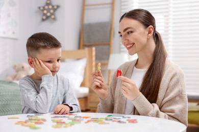 Photo of Dyslexia. Mother and her son learning letters at table indoors