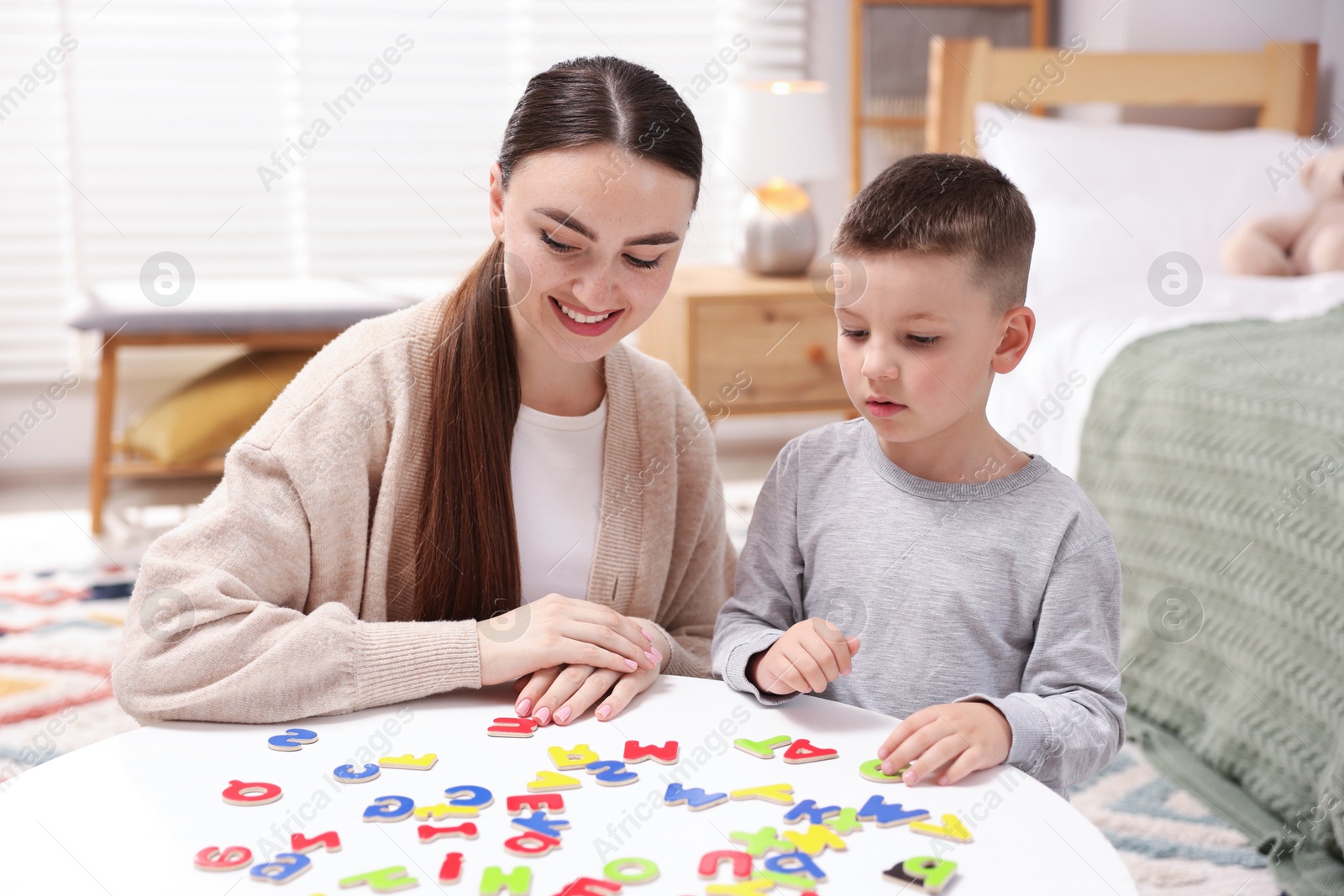 Dyslexia. Mother and her son learning letters at table indoors Photo of Dyslexia. Mother and her son learning letters at table indoors