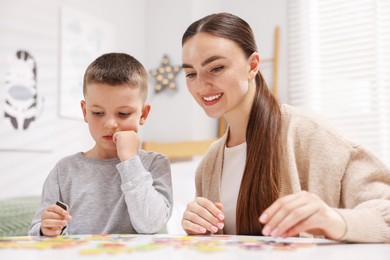Photo of Dyslexia. Mother and her son learning letters at table indoors