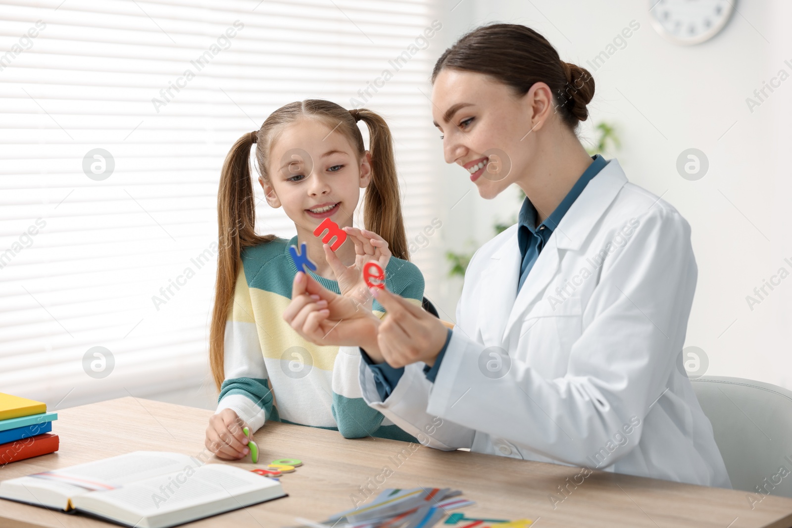 Dyslexia treatment. Pediatrician working with little girl at table indoors Photo of Dyslexia treatment. Pediatrician working with little girl at table indoors