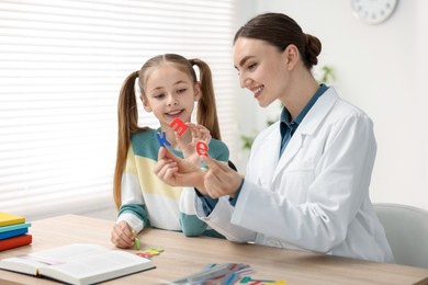 Photo of Dyslexia treatment. Pediatrician working with little girl at table indoors