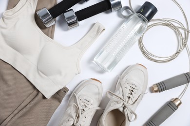 Photo of Sportswear, sneakers, dumbbells, skipping rope and water bottle on white background, flat lay