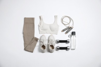 Photo of Sportswear, sneakers, dumbbells, skipping rope and water bottle on white background, flat lay