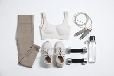 Photo of Sportswear, sneakers, dumbbells, skipping rope and water bottle on white background, flat lay