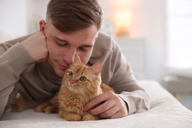 Photo of Man with cute ginger cat on sofa at home, selective focus