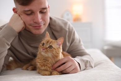 Photo of Man with cute ginger cat on sofa at home, selective focus