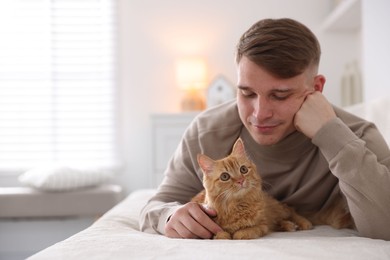Photo of Man with cute ginger cat on sofa at home, space for text