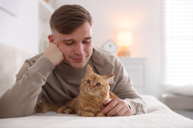 Photo of Man with cute ginger cat on sofa at home, selective focus