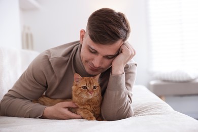 Photo of Man with cute ginger cat on sofa at home
