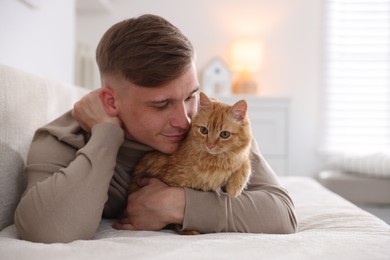 Photo of Man with cute ginger cat on sofa at home