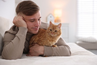 Photo of Man with cute ginger cat on sofa at home