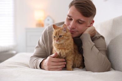 Photo of Man with cute ginger cat on sofa at home, selective focus