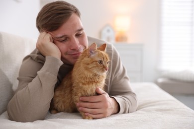 Photo of Man with cute ginger cat on sofa at home, selective focus