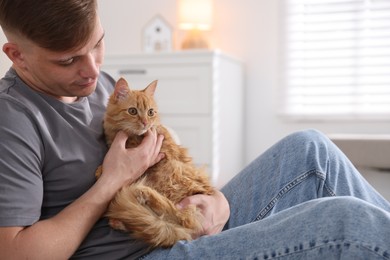 Photo of Man with cute ginger cat at home