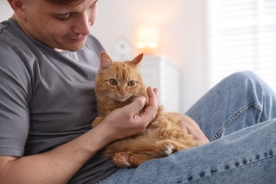 Photo of Man with cute ginger cat at home