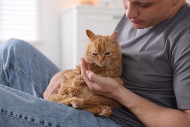 Photo of Man with cute ginger cat at home