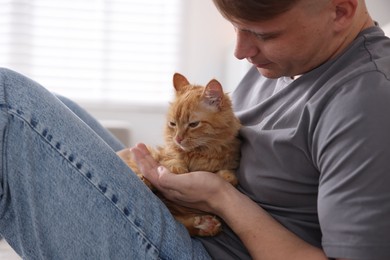 Photo of Man with cute ginger cat at home