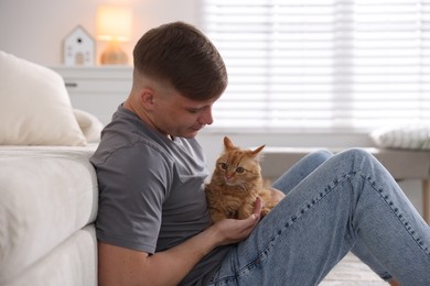 Photo of Man with cute ginger cat at home