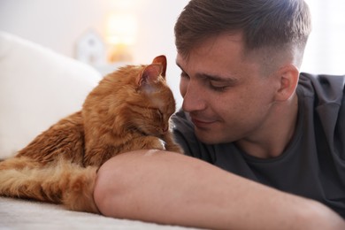 Photo of Man with cute ginger cat on sofa at home