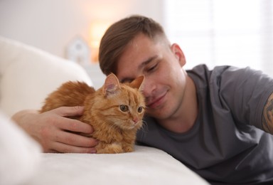 Photo of Man with cute ginger cat on sofa at home, selective focus